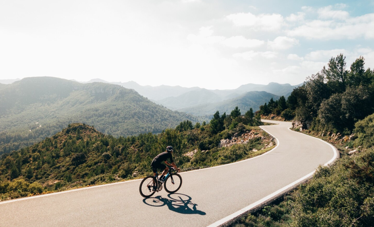 Cyclist riding a bike at sunset in a mountain road
