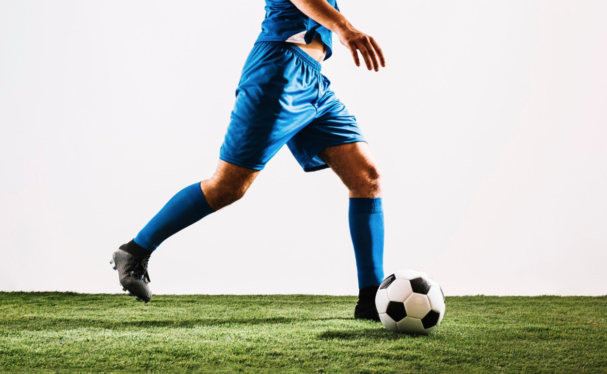 Crop football player shooting ball